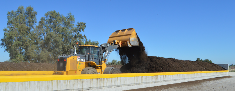 Tractor pouring compost into covered aerated static compost row.